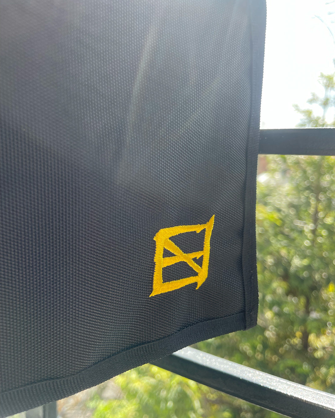 Detalle del logo de Ene Ediciones, hilo amarillo sobre lona negra.