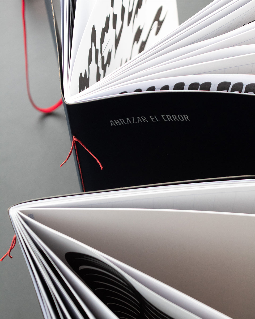 Detalle de la costura con hilo rojo al caballete de la libreta "Abrazar el error". Hojas blancas, portada azul.